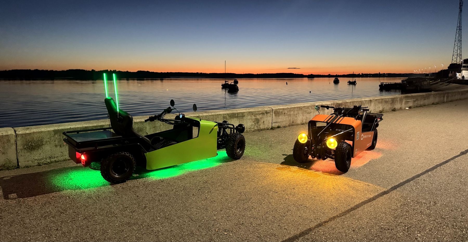Two rides with lights on at sunset by the water